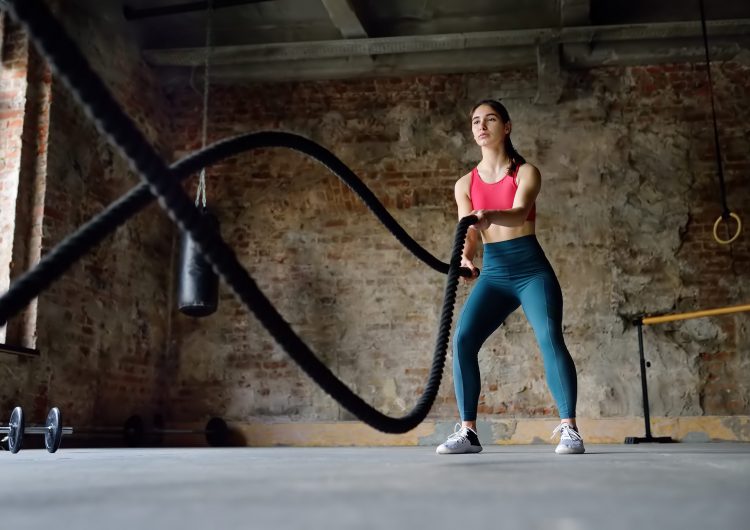 Young,Woman,Exercising,With,Battle,Ropes,At,The,Gym.,Strong